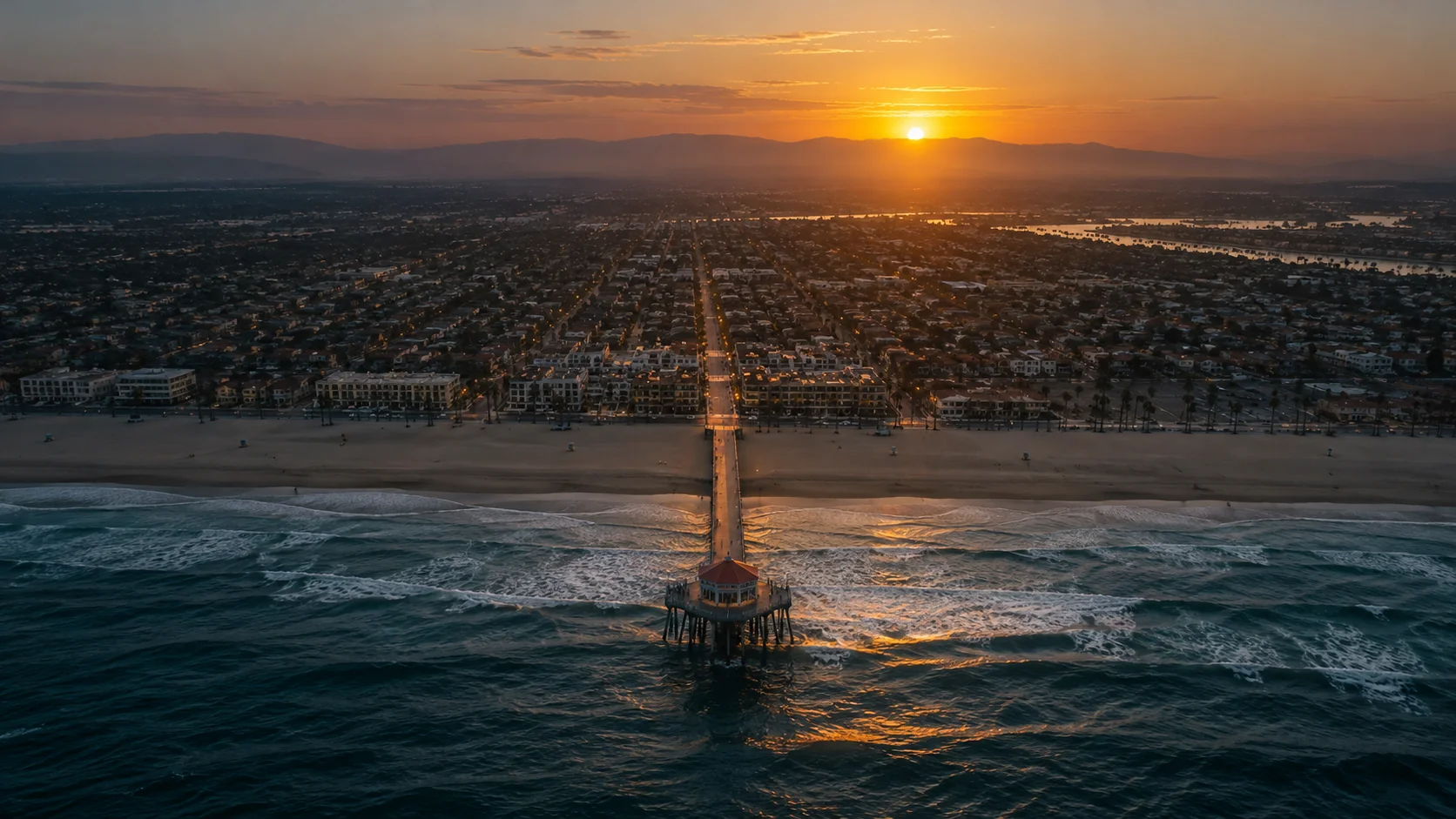 Aerial view at golden hour of Huntington Beach and Orange County neighborhoods with the coastline and pier